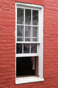 white opened window stands out against the painted red bricks